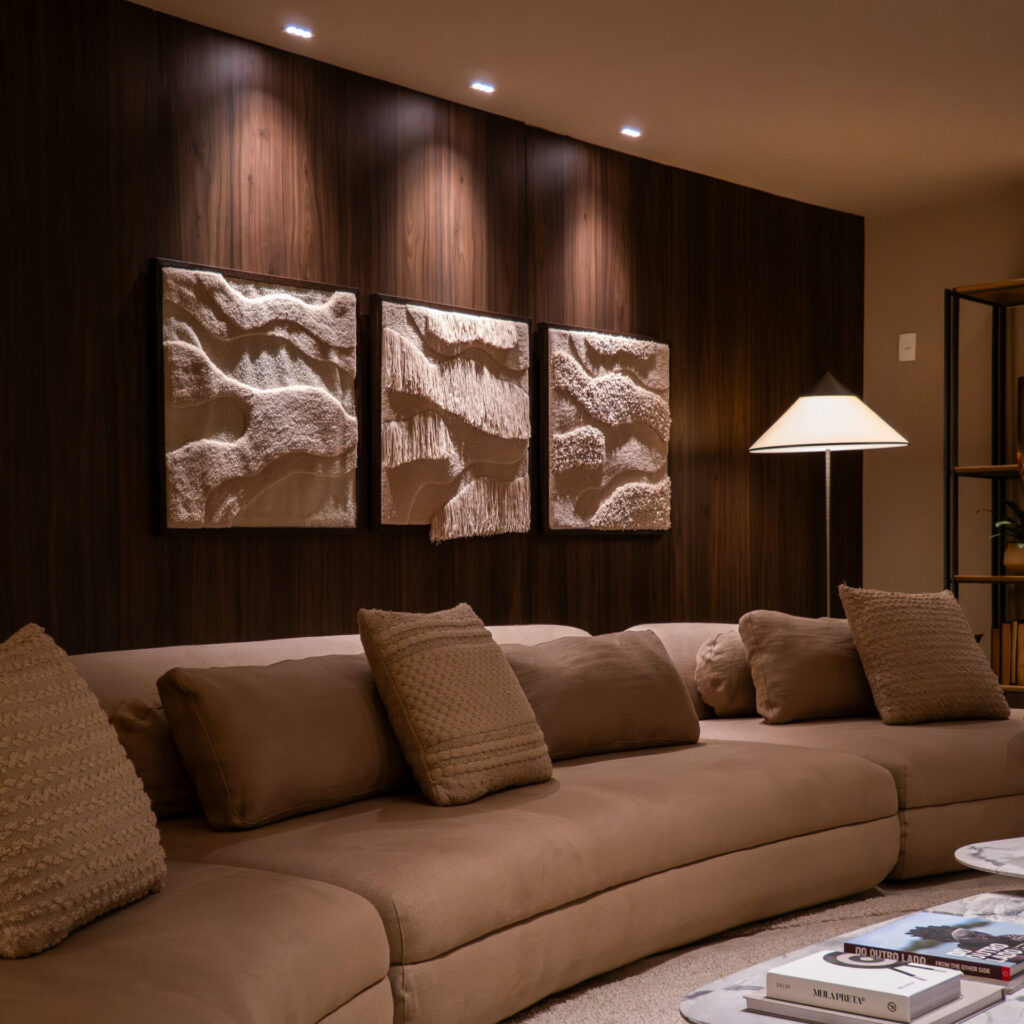 Iluminação estratégica valorizando painel de madeira e obras de arte