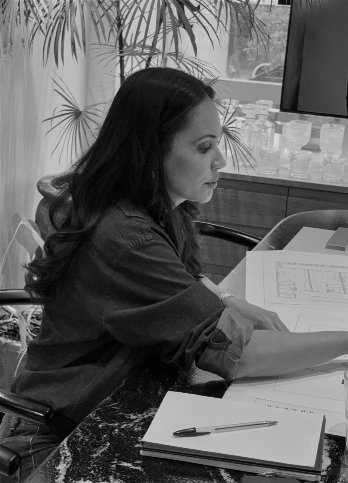 Arquiteta Leila Dionizios analisando as pranchas de um projeto de arquitetura no escritório