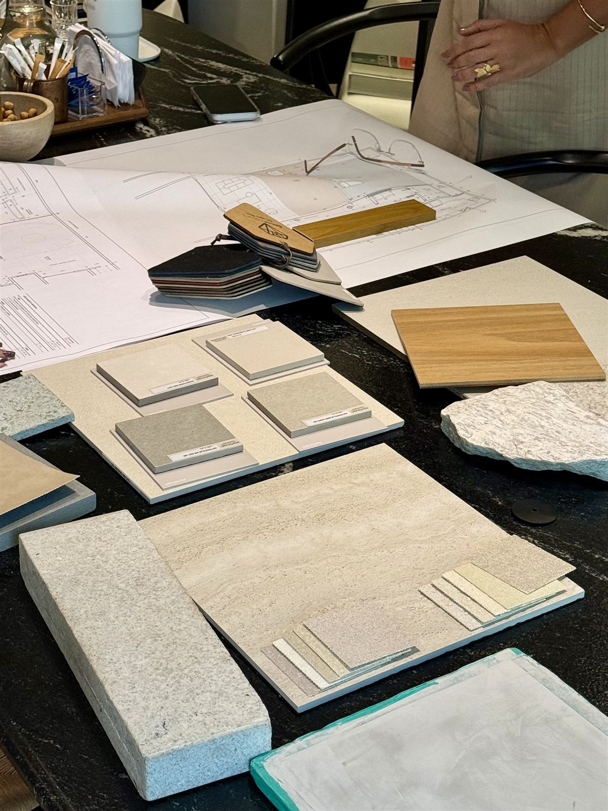 Amostras de pedras naturais, revestimentos e madeiras sobre a mesa durante a curadoria de materiais de um projeto de arquitetura