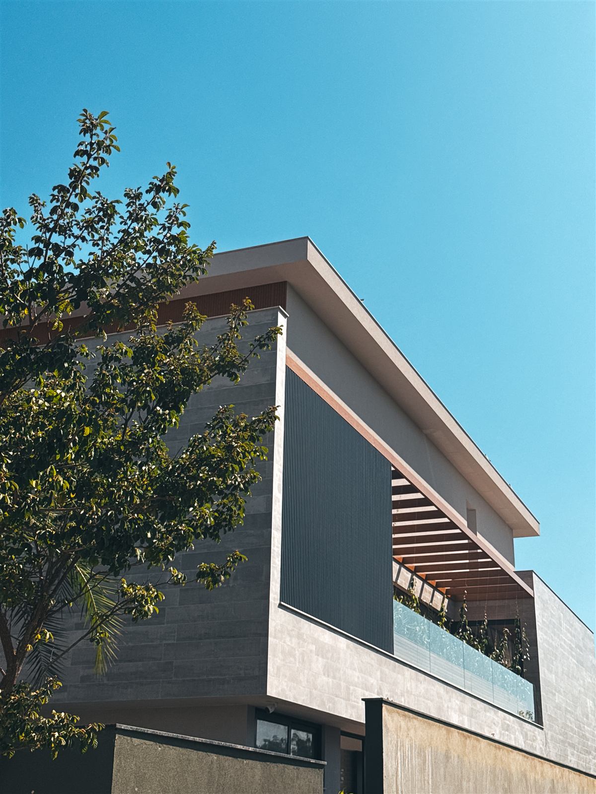 Fachada de casa de alto padrão com brises e pergolado de madeira, resultado de projeto de arquitetura completo